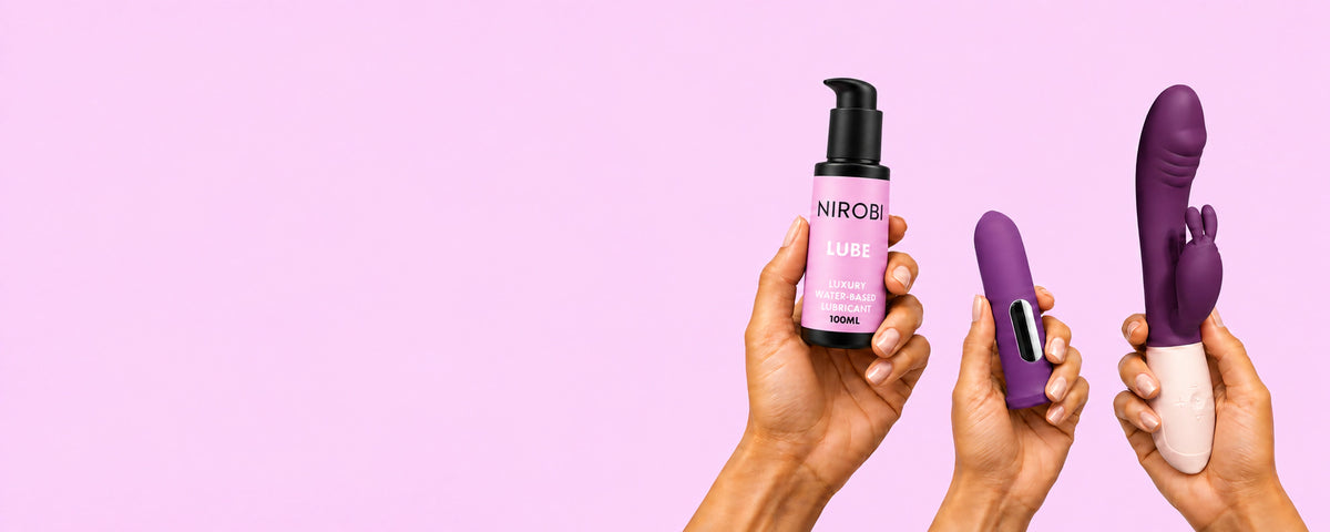 Three hands holding NIROBI water-based lube, a purple bullet vibrator and a purple rabbit vibrator against a pink background.